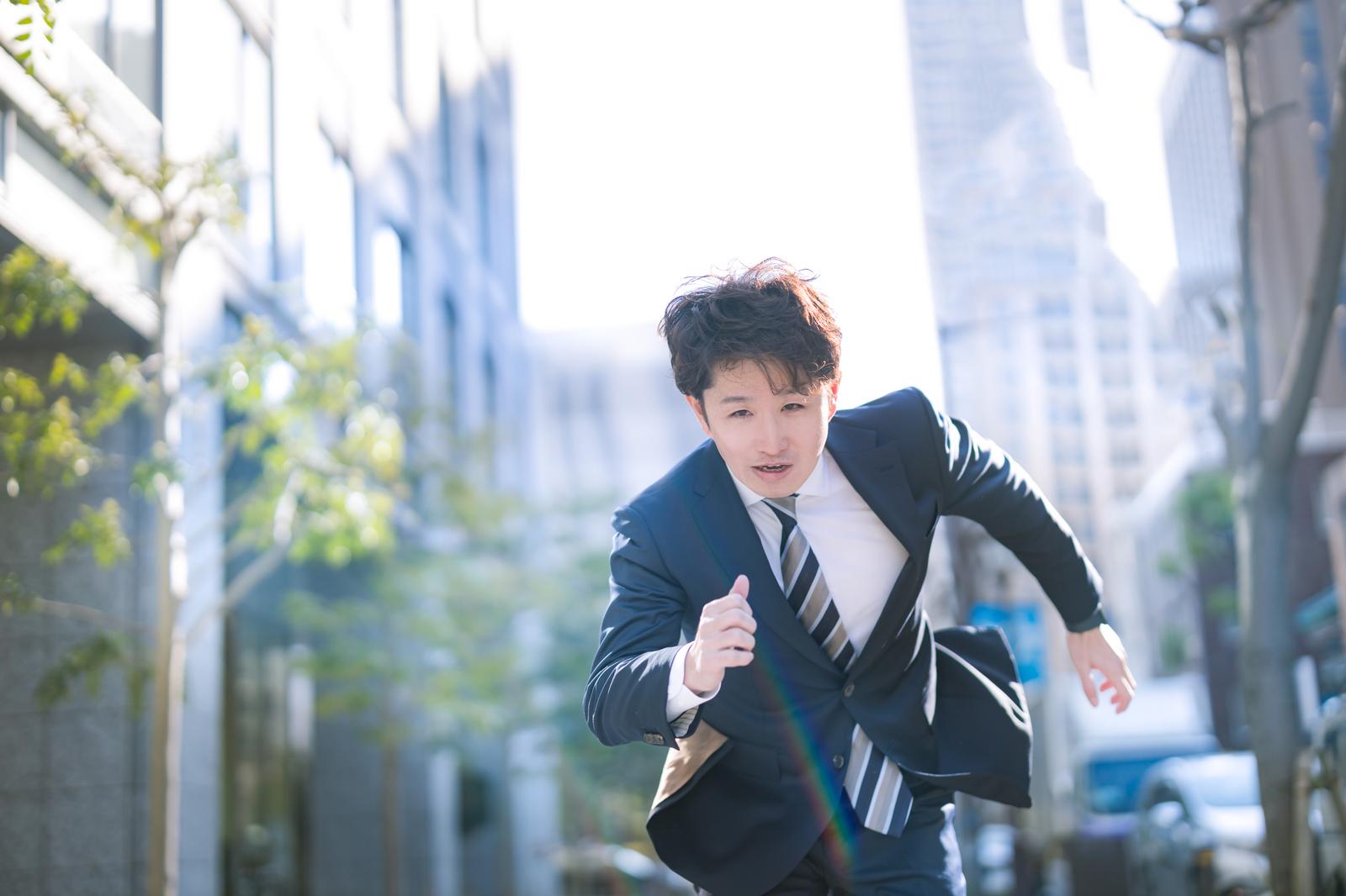ビル街をダッシュするスーツ姿の男性［モデル：野崎繁裕］