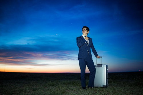 夜明けの草原でスーツ姿で次の目的地へ向かうビジネスマン