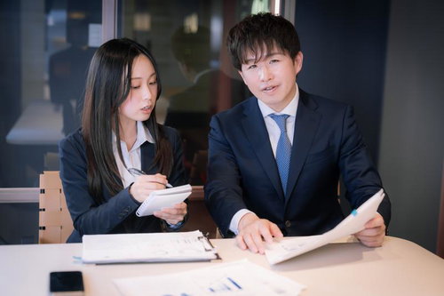 資料を確認しながら説明するM&Aアドバイザーの上司と部下