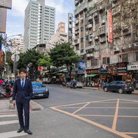 台湾の繁華街を歩くビジネスマン、紺色スーツでまっすぐ前を向くの写真