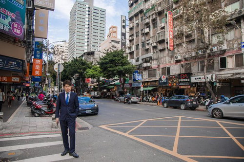 台湾の繁華街を歩くビジネスマン、紺色スーツでまっすぐ前を向く