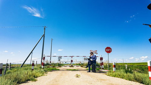 モンゴルの踏切前でパソコンを広げるビジネスマン