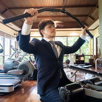 出筋前のスーツ姿でジムのラットプルマシンを使う男性の写真