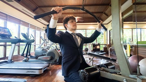 出筋前のスーツ姿でジムのラットプルマシンを使う男性