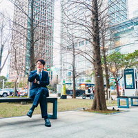 オフィス街のベンチで休憩する紺色スーツの男性ビジネスマンの写真