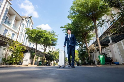 出張日和のスーツ姿の元銀行マンとキャリーケース