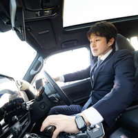 運転席でハンドルを握るスーツ姿のビジネスマンの写真