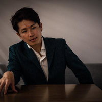 ブラインドの隙間から覗き見る怪しい雰囲気の眼鏡姿の男性の写真