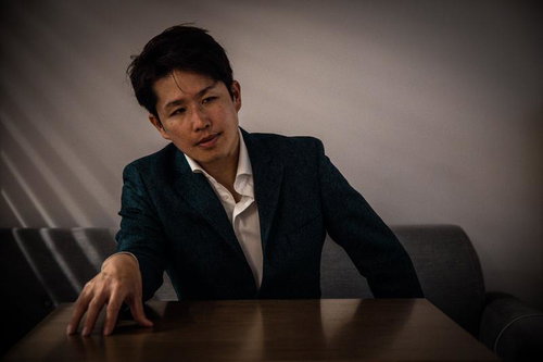 ブラインドの隙間から覗き見る怪しい雰囲気の眼鏡姿の男性