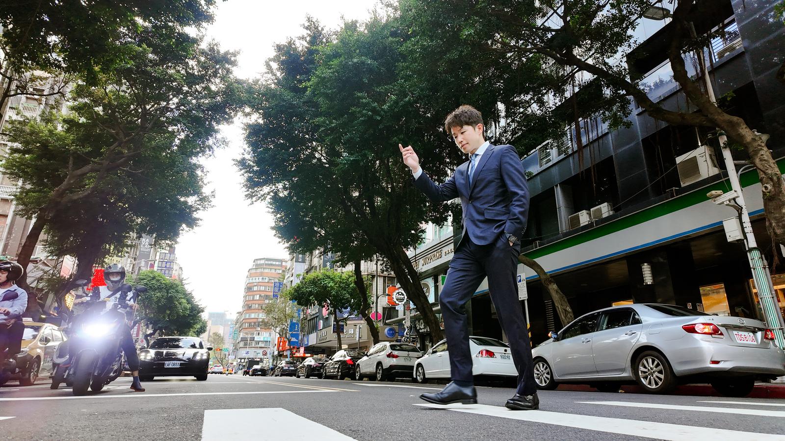 スーツ姿の男性がアンコール・トムの南大門前でスーツケースを引いている［モデル：野崎繁裕］