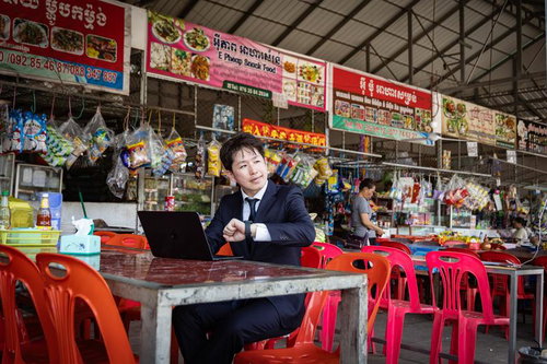 カンボジアのフードコートでノートPCを操作するスーツ姿の男性