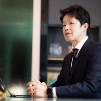 オフィスでノートパソコンを使い打ち合わせする男性の写真