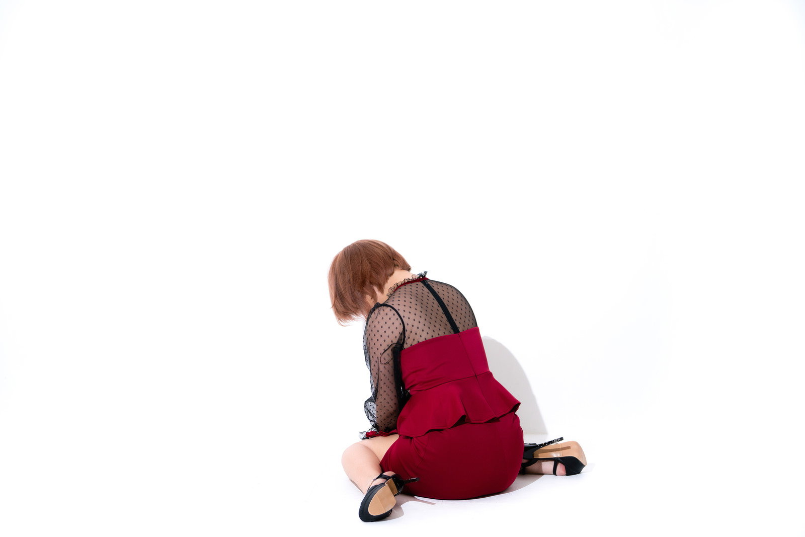 赤いドレスを着た女性が床に座り込み項垂れている後ろ姿［モデル：にゃるる］