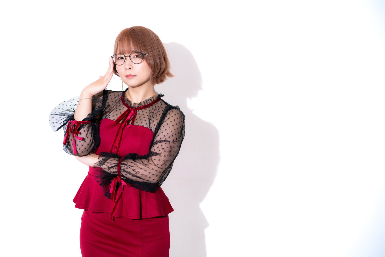 赤いパーティードレスを着て腕を組むポーズをとる黒縁眼鏡の女性［モデル：にゃるる］