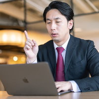 リモート会議中に「おぼろげながら浮かんできたんです。」と提案する偉い役職の人の写真
