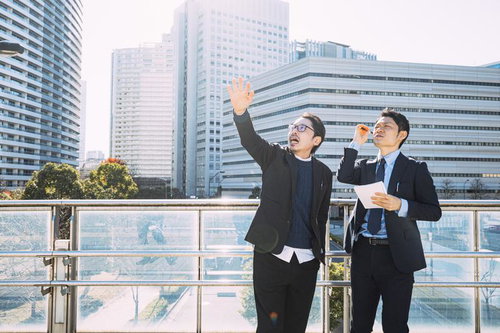 屋外で営業担当と打ち合わせを行う上司の男性