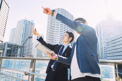 ビルを指して説明する建築視察中の会社員男性