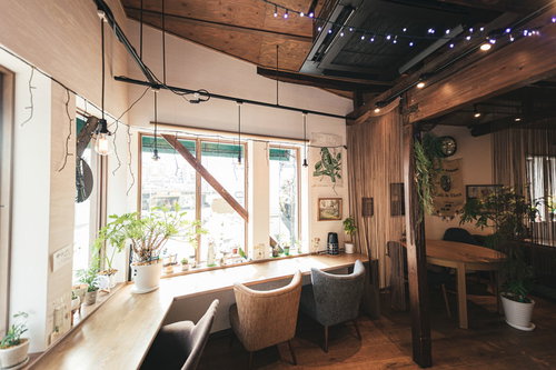 カフェの窓際の席に置かれた観葉植物と木製テーブル