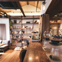 木製カウンターに並ぶティードリッパーのカフェの写真