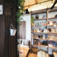 カフェの木製の柱と観葉植物でくつろぐ店内空間の写真