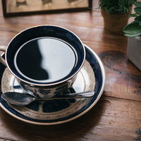 リフレクションしそうなブラックコーヒーとカップの写真
