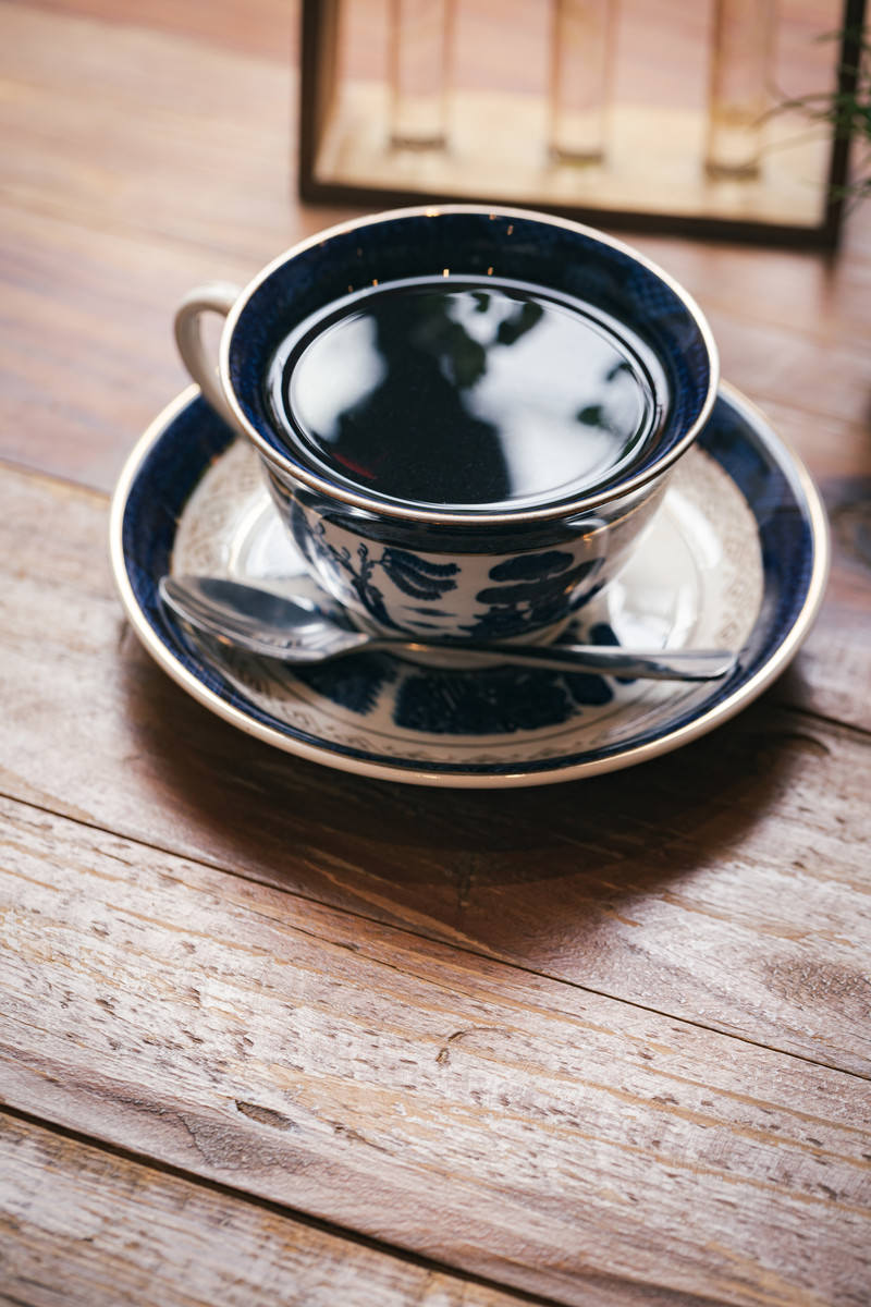 木製のテーブルの上に置かれた黒いコーヒーカップとソーサー