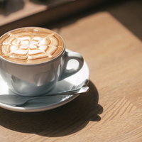 カフェの木製テーブルに置かれたラテアートの写真
