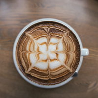 白いカップに描かれた花模様のデザインカプチーノの写真