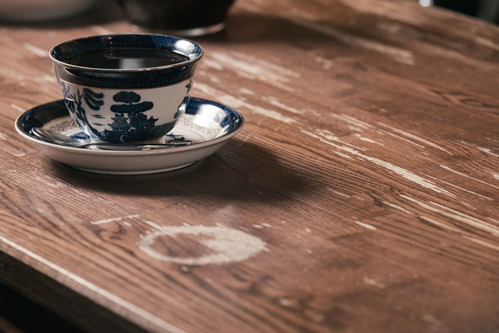 木製カウンターの上に置かれた深い色のコーヒーカップとソーサー