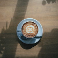 青いカップに描かれたクローバーのラテアートの写真