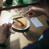 ホットケーキを食べる手元、フォークで切り分ける瞬間の写真