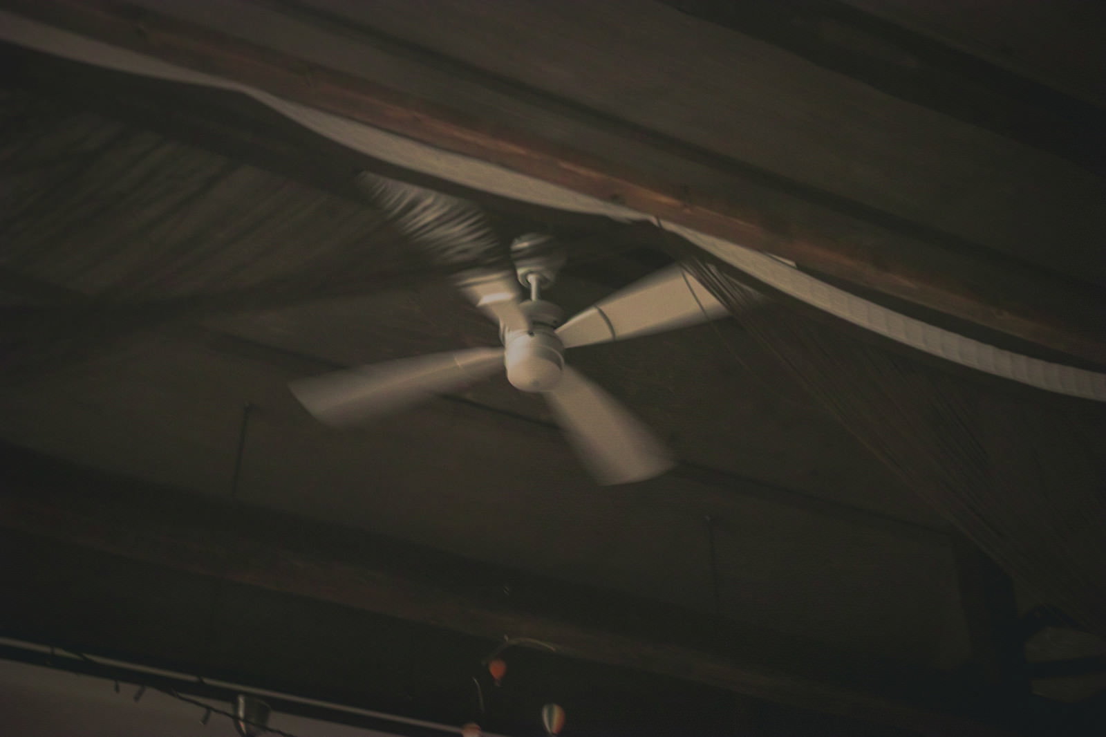 薄暗い部屋の天井で静かに回転している白いシーリングファン