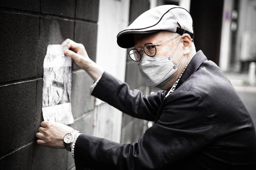 怪文書を壁に貼る高齢の男性