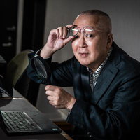 ルーペと眼鏡を手にするスーツの男性の写真