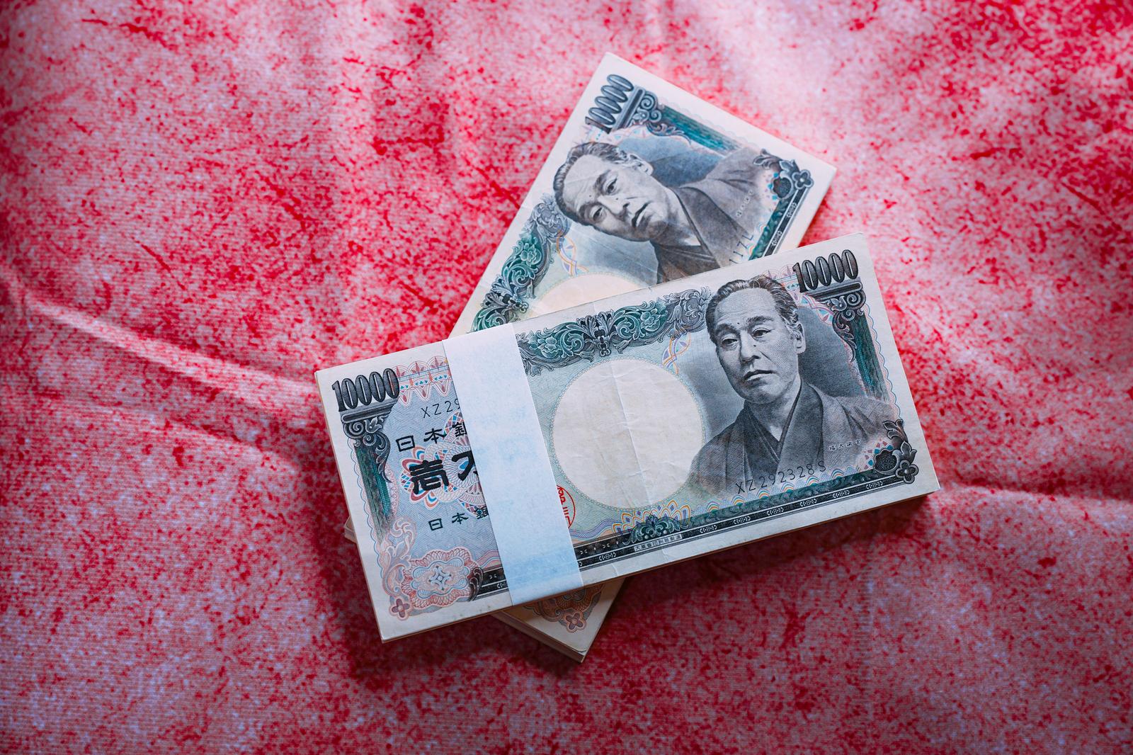 ピンクの背景に積み重ねられた帯付きの一万円札