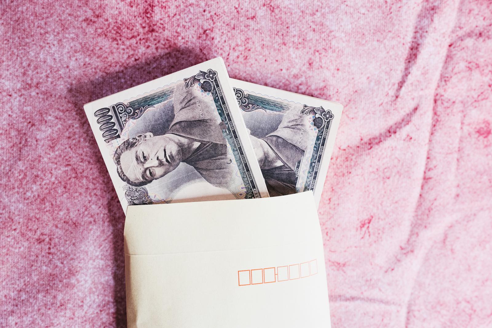 茶色い封筒から顔をのぞかせる一万円札の札束