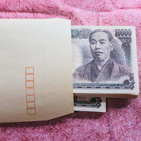 茶封筒から顔を出した一万円札の現金と賄賂の写真