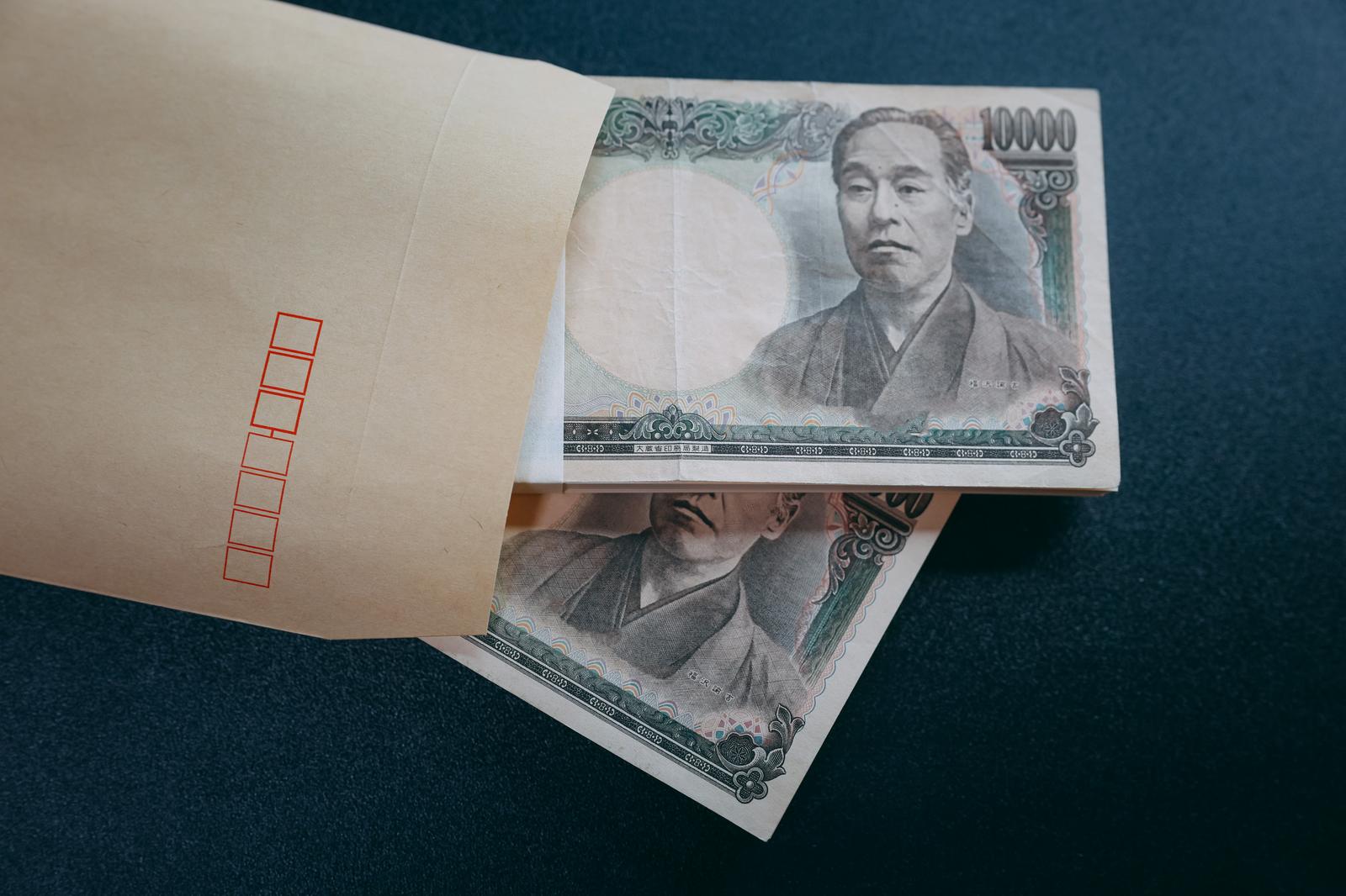 茶封筒から出た一万円札の札束が机の上に広げられている