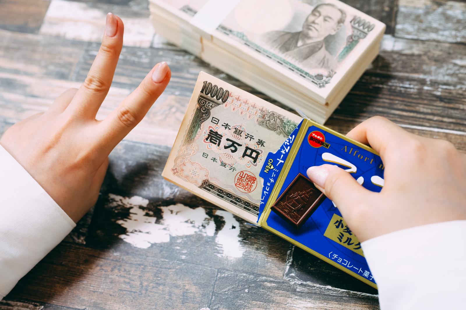 札束と一万円札を手に持ってピースサインする子どもの手元