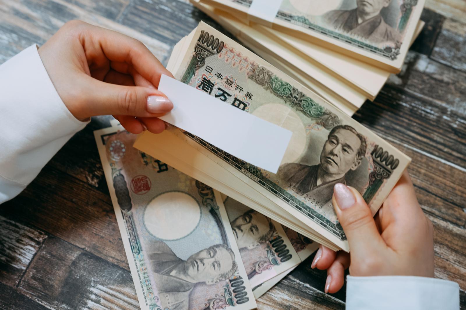 ID番号付きのお札を白い封筒から取り出す手元と札束