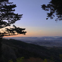 朝焼けに染まる空と山の中腹から見下ろす町並みの写真