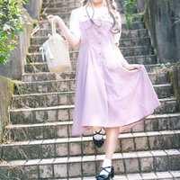 薄いピンクのワンピース姿で階段を降りる女性の写真