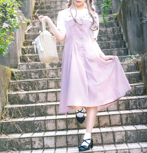 薄いピンクのワンピース姿で階段を降りる女性