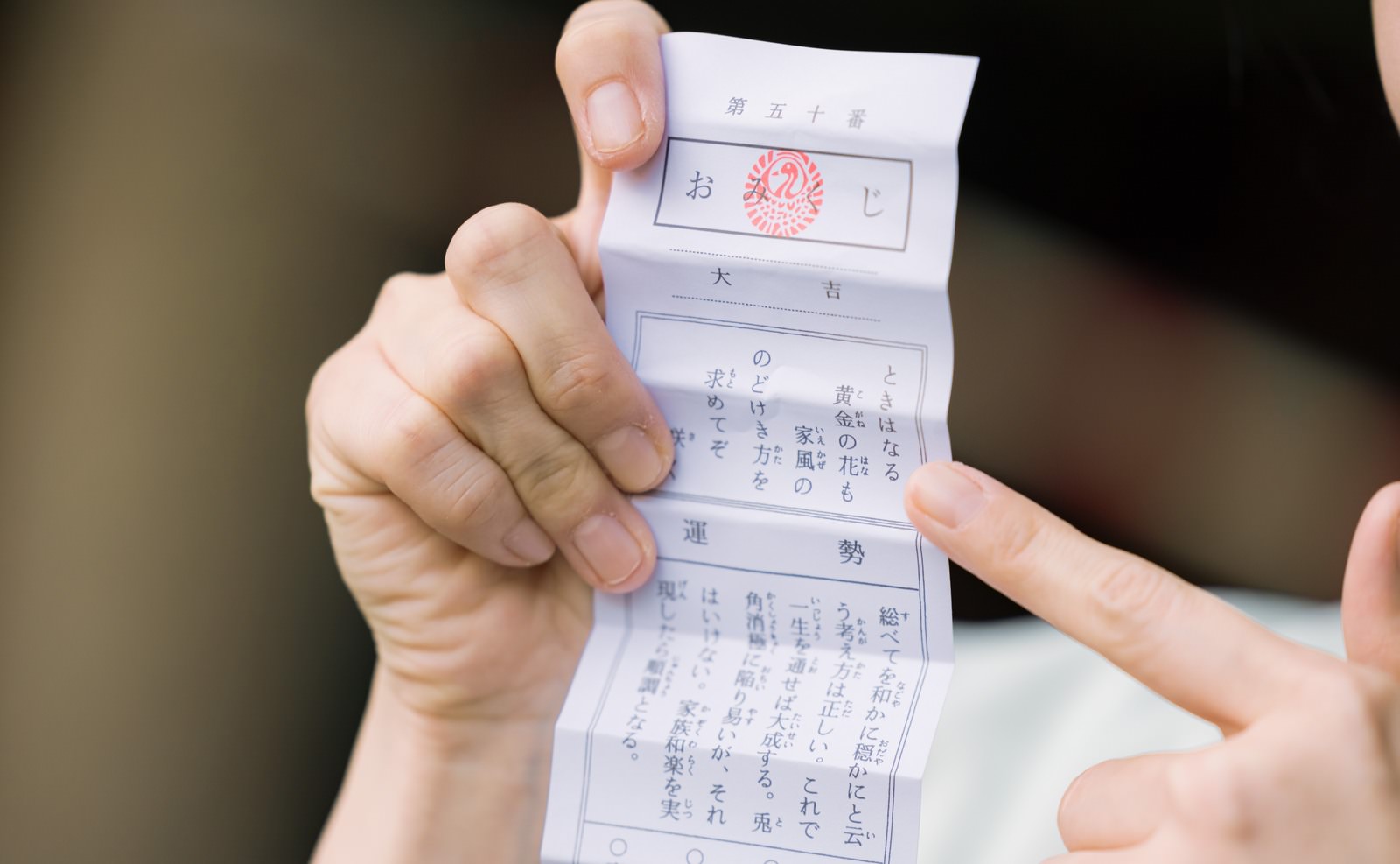 A hand holding an omikuji with the 'daikichi' (great blessing) result