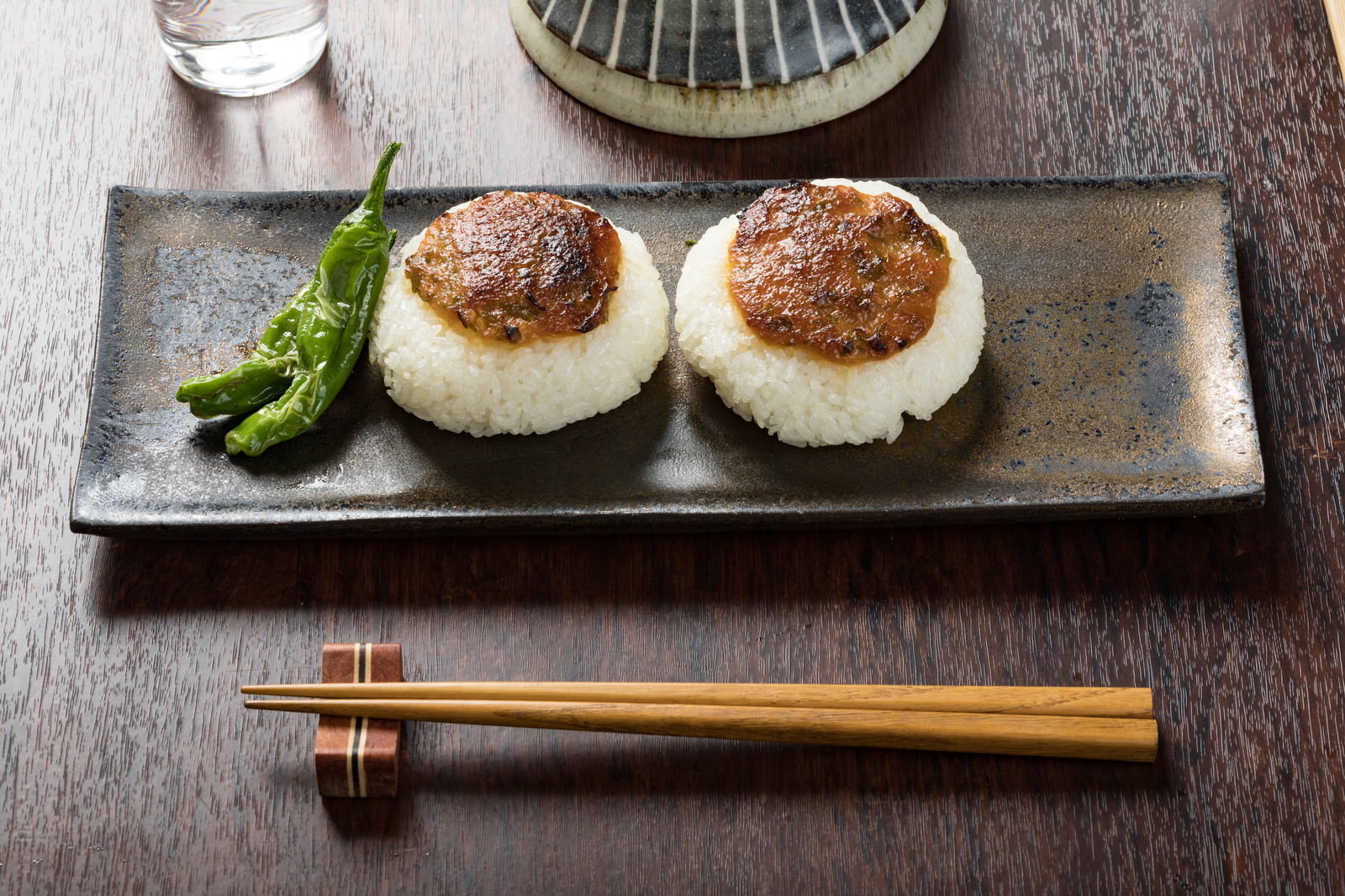 石皿の上に盛り付けられた味噌焼きおにぎり2個とししとう