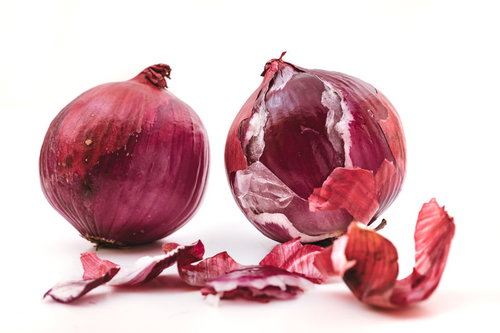 皮を剥いたレッドオニオンと散らばった薄い表皮