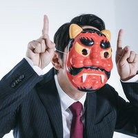 プンスカ社員・鬼の面をかぶって激怒するスーツ姿の男性の写真