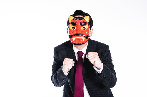 鬼の面をつけたスーツ姿の男性がファイティングポーズを取る