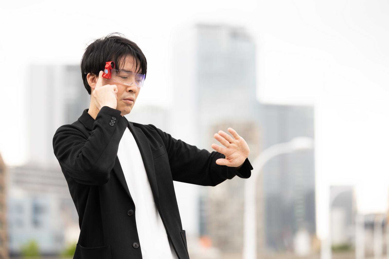エナジードリンクが並ぶ机でパソコン作業をする人物［モデル：金子周平］