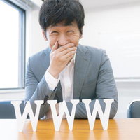 字幕がでる世界で口を手で押さえて笑う男性の写真